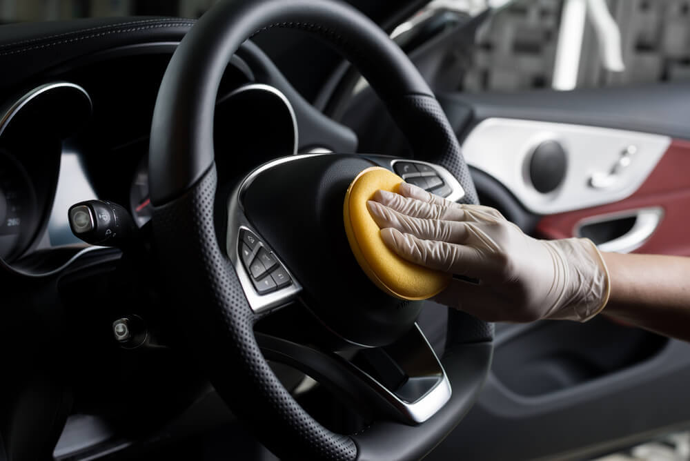 a cleaner using a polishing pad on the upholstery of a car