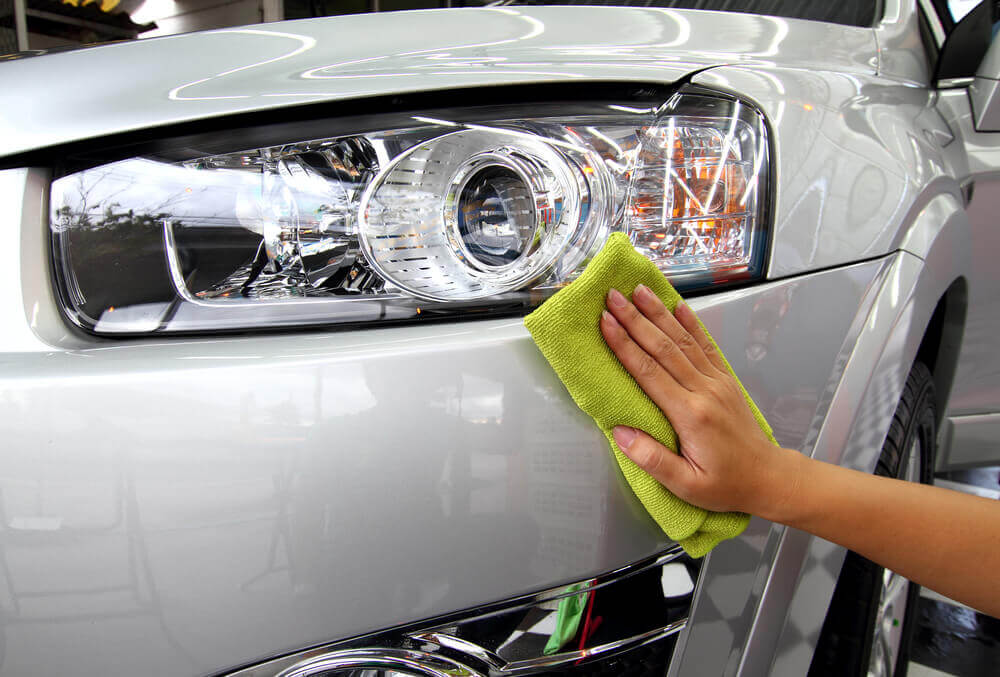 a close up shot of a very clean silver car's headlight being wiped over with a cloth